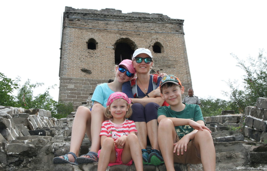 mom and three kids sitting at the Great Wall of China