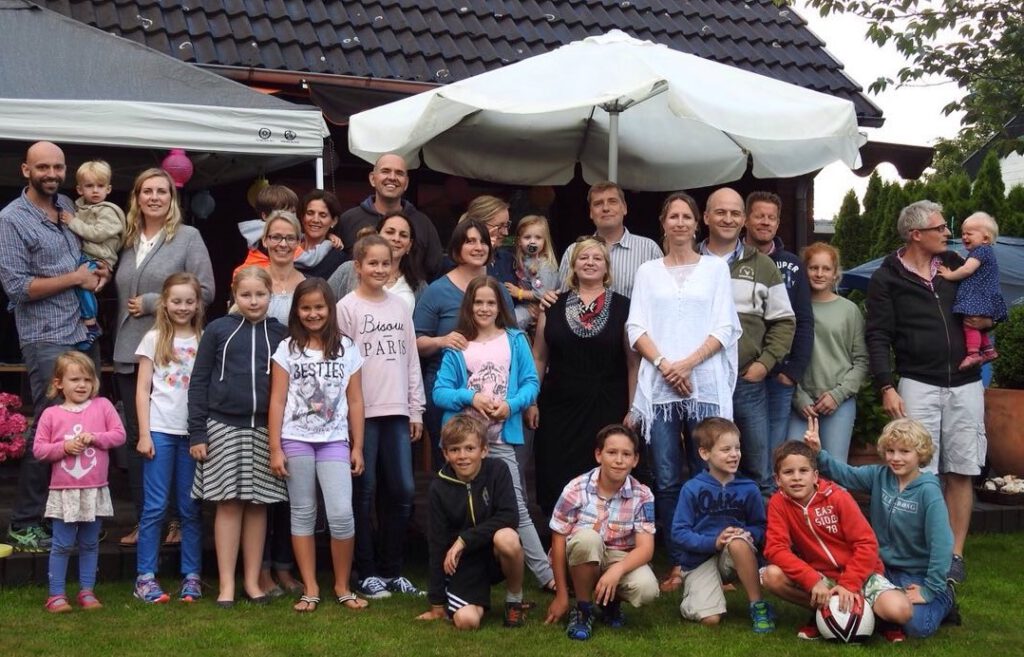 group of parents and children standing in a garden in summer.